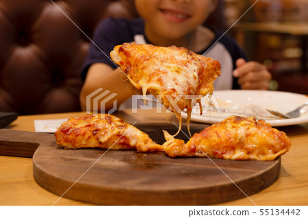 Young boy smiling and taking slice of pizza on wooden tray. Young boy smiling and taking slice of pizza on wooden tray. 55134442