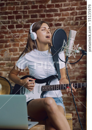 Woman recording music, playing guitar and singing at home 55135976
