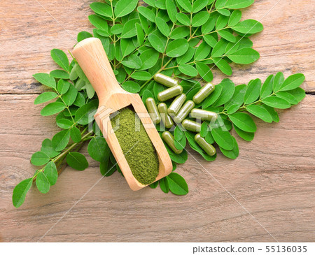 moringa leaf and powder capsule on a wooden moringa leaf and powder capsule on a wooden 55136035