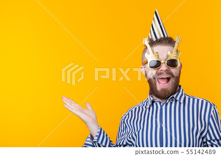 Crazy young positive hipster guy with a beard laughs happily on a yellow background with copy space Crazy young positive hipster guy with a beard laughs happily on a yellow background with copy space 55142489