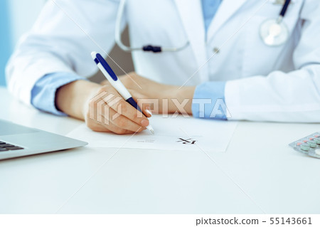 Female doctor filling up prescription form while sitting at the desk in hospital closeup. Healthcare 55143661