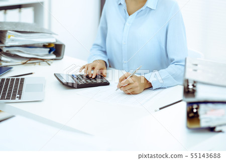 Unknown female bookkeeper or financial inspector calculating or checking balance, making report 55143688