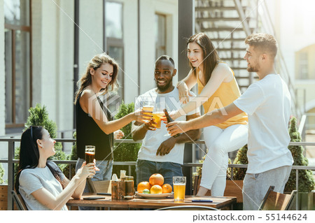 Young group of friends drinking beer and celebrating together Young group of friends drinking beer and celebrating together 55144624