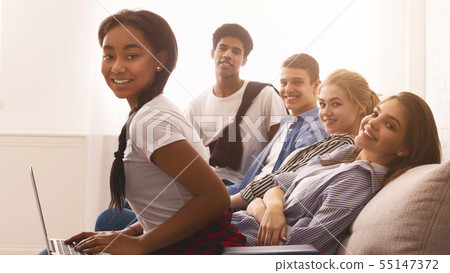 Multiracial teen students resting with books and laptop on sofa Multiracial teen students resting with books and laptop on sofa 55147372