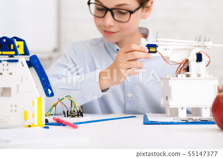 Concentrated boy constructing robot at class, closeup Concentrated boy constructing robot at class, closeup 55147377