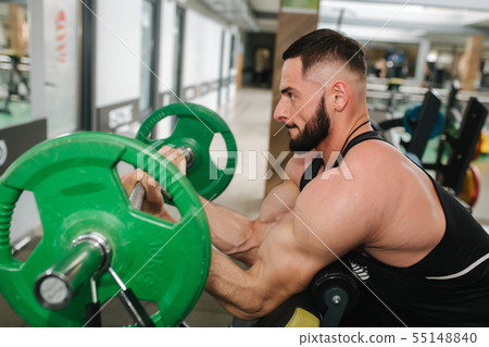 A young athlete trains in the gym. Trians biceps muscules 55148840
