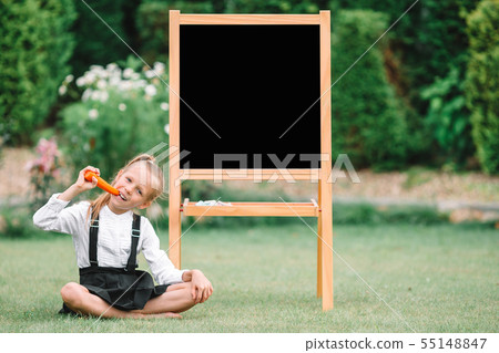 Happy little schoolgirl with a chalkboard outdoor 55148847