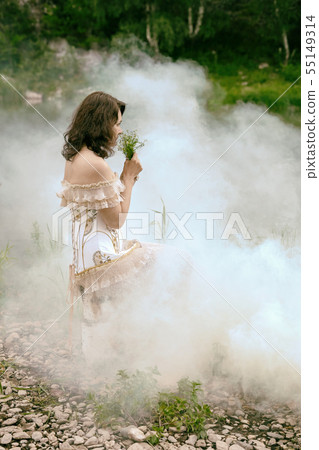 Girl with a bouquet of wild flowers in a misty 55149314