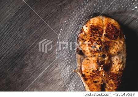 Close-up one grilled cum salmon keta fish steak on a glass transparent plate on a dark wood table 55149587