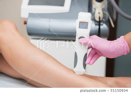 Specialist makes skin tone measurements on a womans leg Specialist makes skin tone measurements on a womans leg 55150934