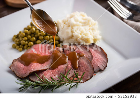 pouring gravy sauce on sliced roasted beef with pouring gravy sauce on sliced roasted beef with 55152938
