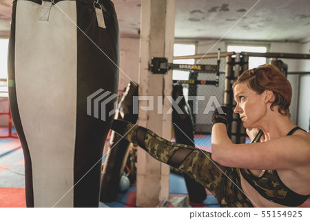 Gorgeous woman, mma fighter in gym during training. Preparing for a hard caged match Gorgeous woman, mma fighter in gym during training. Preparing for a hard caged match 55154925