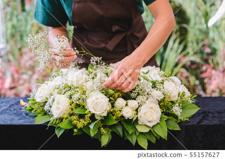 Gardener woman creating grave decoration 55157627