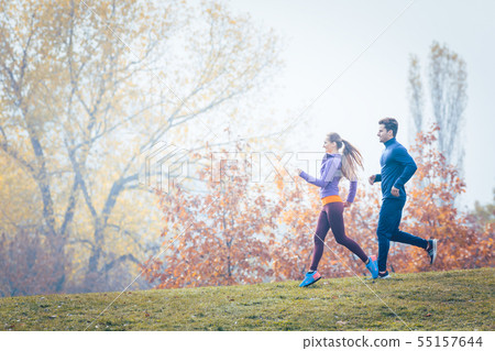 Woman and man jogging or running in park during autumn 55157644