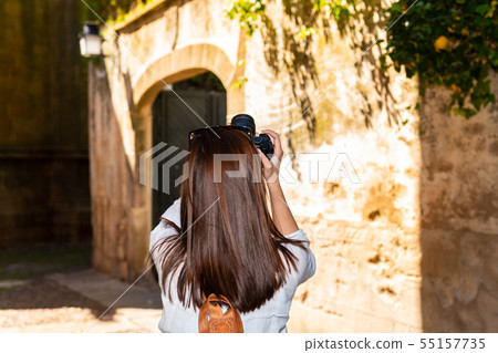 A young red-haired tourist takes photographs with her camera of the narrow streets of the old town 55157735