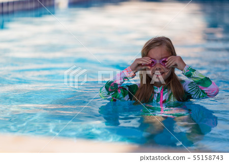 Smiling baby girl wearing swimming glasses in swimming pool 55158743