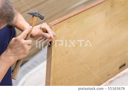 Interior work A joiner crafts processing a sliding door with a chisel in order to attach a door wheel Interior work A joiner crafts processing a sliding door with a chisel in order to attach a door wheel 55165676