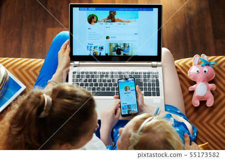 mother and child checking social media on laptop and smartphone 55173582