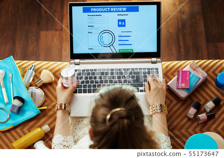 woman with creme writing review on laptop after online shopping 55173647