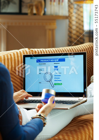 woman with creme writing review on laptop after online shopping woman with creme writing review on laptop after online shopping 55173743