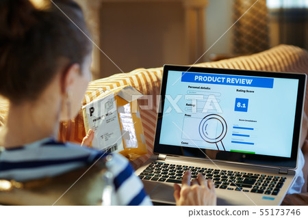 woman writing review on laptop after online shopping fast delive woman writing review on laptop after online shopping fast delive 55173746