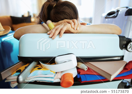 tired stylish woman relaxing on over packed suitcase tired stylish woman relaxing on over packed suitcase 55173870