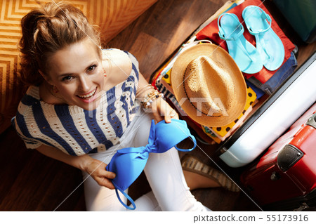 elegant woman packing bikini in open travel suitcase elegant woman packing bikini in open travel suitcase 55173916