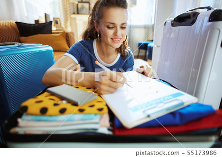 happy elegant traveller woman checking luggage plan 55173986