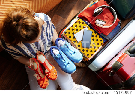 woman packing fashion and comfortable shoes in travel suitcase 55173997