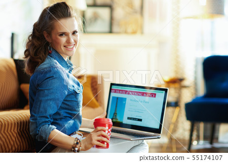 woman with red coffee cup and online travel site on laptop woman with red coffee cup and online travel site on laptop 55174107
