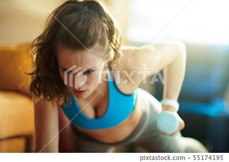 fit sports woman with blue dumbbell workout at modern home 55174195