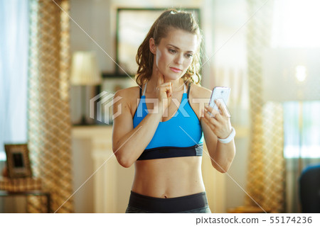 young woman using smartphone to check pulse rate young woman using smartphone to check pulse rate 55174236