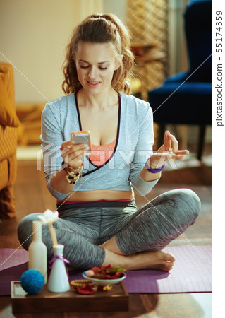 sports woman watching yoga tutorial on internet via smartphone sports woman watching yoga tutorial on internet via smartphone 55174359