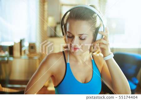 young woman listening to music with headphones in modern house 55174404