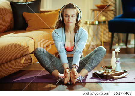 sports woman in white headphones in modern house meditating 55174405