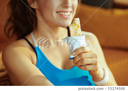 Closeup on smiling young sports woman eating fitness bar 55174500