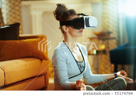 Closeup on sports woman in modern house doing yoga in VR gear Closeup on sports woman in modern house doing yoga in VR gear 55174794