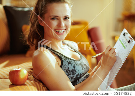 smiling woman with apple and clipboard filling meal plan smiling woman with apple and clipboard filling meal plan 55174822