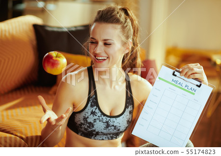 woman holding clipboard with meal plan and throwing apple up woman holding clipboard with meal plan and throwing apple up 55174823