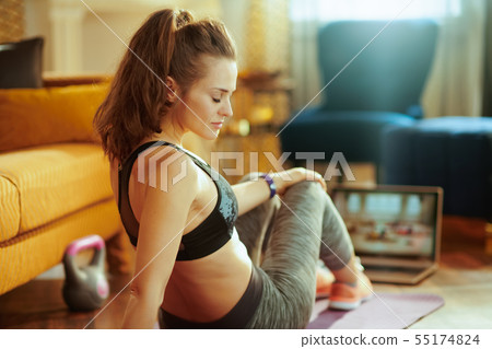woman and watching fitness tutorial on internet via laptop woman and watching fitness tutorial on internet via laptop 55174824