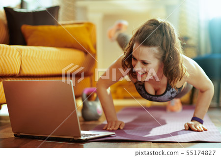woman watching tutorial on internet and doing pushups woman watching tutorial on internet and doing pushups 55174827