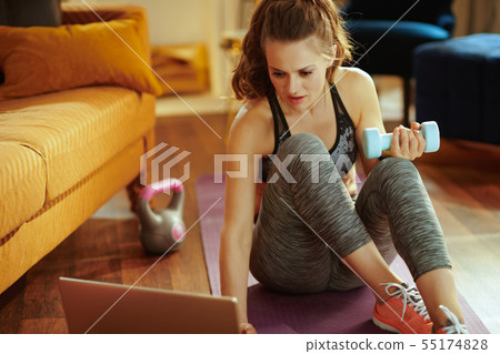 sports woman with dumbbell using laptop to share workout results 55174828