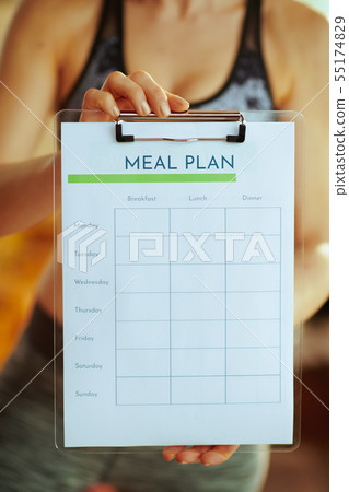 Closeup on fit woman showing clipboard with meal plan Closeup on fit woman showing clipboard with meal plan 55174829