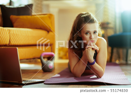 sports woman with laptop laying on fitness mat at modern home sports woman with laptop laying on fitness mat at modern home 55174830