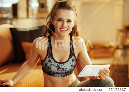 woman using online personal fitness trainer service in tablet PC 55174887