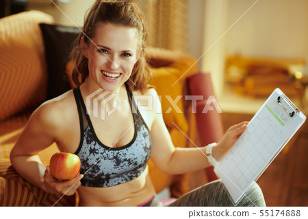 happy sports woman holding apple and clipboard with meal plan happy sports woman holding apple and clipboard with meal plan 55174888