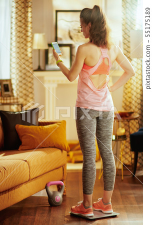 woman looks at results recieved from smart scale 55175189