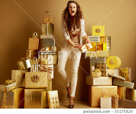happy fashion-monger with gift box in front of a plain wall happy fashion-monger with gift box in front of a plain wall 55175820