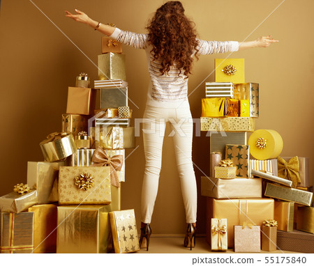 stylish woman among 2 piles of golden gifts rejoicing 55175840