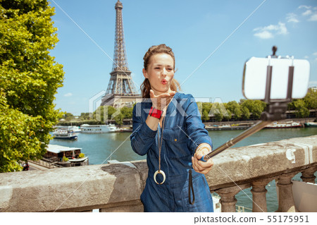 woman taking selfie using selfie stick and blowing air kiss woman taking selfie using selfie stick and blowing air kiss 55175951
